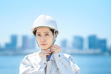 作業着を着てヘルメットを確認する女性