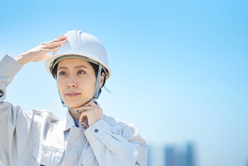 作業着を着てヘルメットを確認する女性