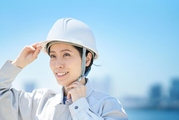 作業着を着てヘルメットを確認する女性