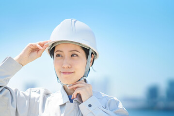 作業着を着てヘルメットを確認する女性