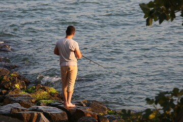 Fototapeta na wymiar Amateur fisherman is fishing on Cengelkoy Coastline at sunset in Istanbul, Turkey.