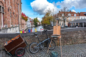 Easel, paint, artist's Bicycle on the stone bridge over the canal in Bruges (Brugge), Flanders, Belgium