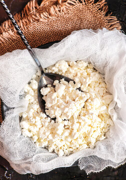 Fresh cottage cheese on gauze on a black background