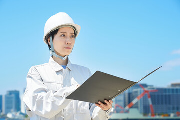 現場を確認する作業着姿の女性