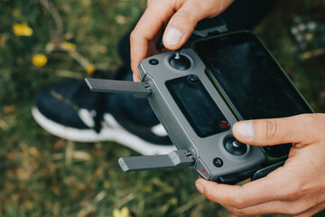 Photograph of a man's hands holding the remote control of a Drone (Drone Operator). Technology concept