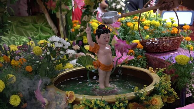 A devotee baths a statue of Buddha during Vesak Day

