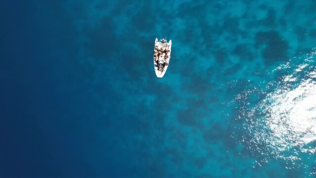 View from top on crystal clear water, coral reef and Divers getting ready to start a dive from a dhingy in Raja Ampat, Yangeffo, Papua, Indonesia