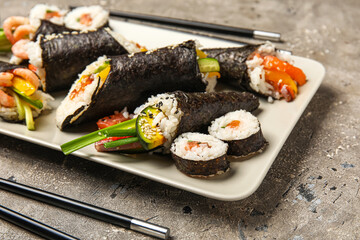 Plate with tasty sushi cones and rolls on grunge background, closeup