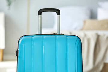 Blue suitcase in light bedroom, closeup
