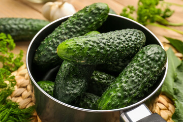 Saucepan with fresh cucumbers for preservation on table, closeup