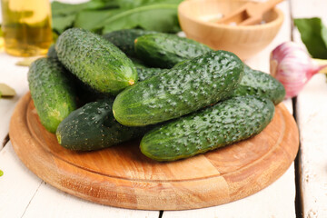 Wooden board with fresh cucumbers for preservation on table