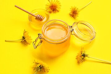 Jar and bowl with dandelion honey on yellow background