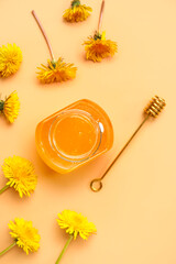 Jar with dandelion honey on orange background
