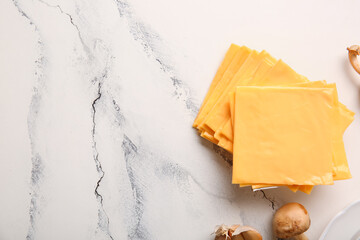 Slices of tasty processed cheese on white marble background