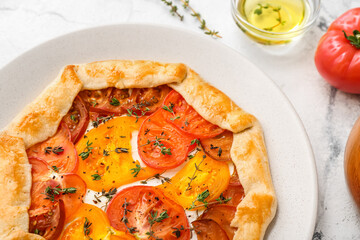 Plate with tasty tomato galette on white background