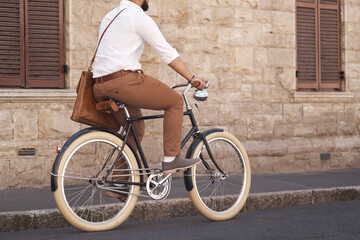 Fototapeta premium Businessman, eco friendly and riding bicycle to work or corporate guy or commuter on urban street and in the morning. Traveling, male professional and carbon neutral bike to the office or transport