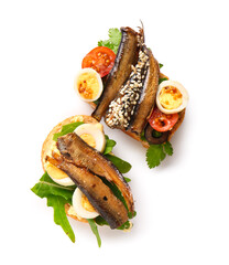 Tasty sandwiches with canned smoked sprats on white background