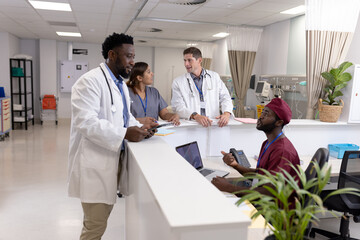 Obraz premium Diverse doctors and medical staff talking at reception desk of hospital ward