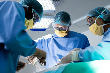 Diverse group of surgeons operating on patient in operating theatre