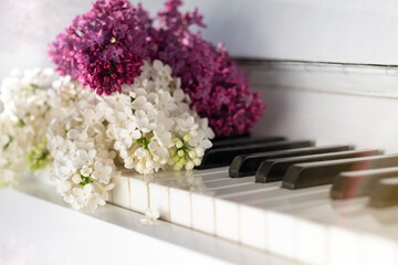 A bouquet of lilacs on the keys of a white piano