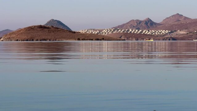 Beautiful bay with calm blue sea, boats, islands and mountains
