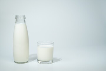 Glass of milk against a white background / Close-up of milk pouring in drinking glass on table