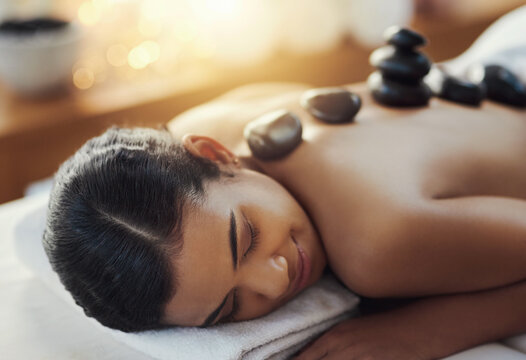 Happy woman, relax and sleeping in rock massage at spa for skincare, beauty or body treatment. Calm female asleep in relaxation with hot rocks or pile on back in therapy, zen or wellness at salon