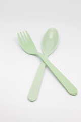 isolated photo of sage color plastic cutlery and chopsticks on a white background