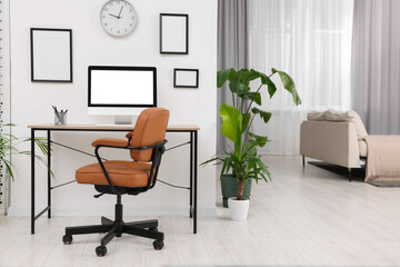 Stylish room interior with comfortable office chair, desk and houseplants