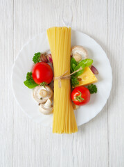 Pasta spaghetti, cheese, vegetables and spices on a white wooden table