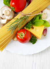 Pasta spaghetti, cheese, vegetables and spices on a white wooden table