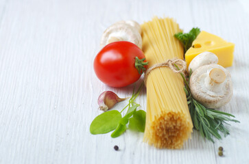 Pasta spaghetti, cheese, vegetables and spices on a white wooden table