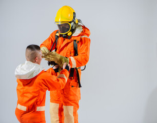 Against a clean white background, the image captures a scene of camaraderie and teamwork as a firefighter assists his colleague in putting on his firefighting gear.