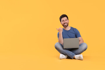 Happy man with laptop on yellow background. Space for text