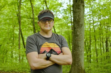 portrait of hiker  tourist man in the woods with glasses and sport shirt and black sun  hat
