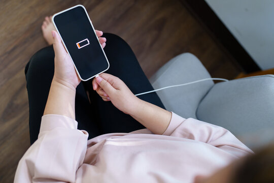 Woman hands Charging mobile phone battery with low battery. plugging a charger in a smart phone  with energy bank powerbank power charger Modern lifestyle energy technology concept