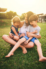 Mother, happy children or hug playing on grass for fun bonding in summer outside a house in nature. Funny mom hugging playful kids siblings on garden playground with happiness of family together