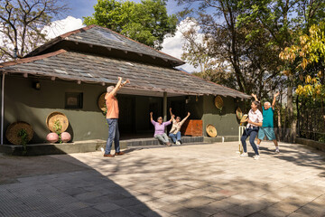 Family members playing cricket in the back yard.
