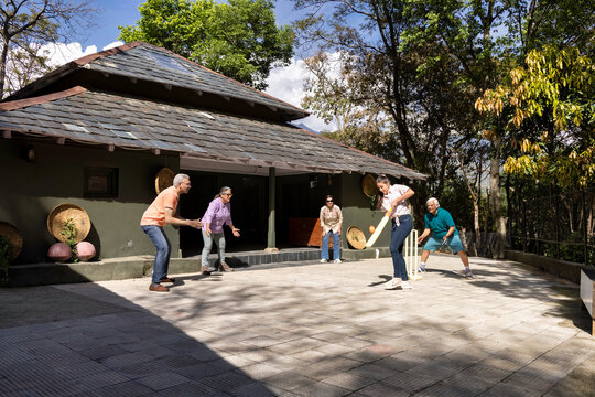 Family Members Playing Cricket In The Back Yard.