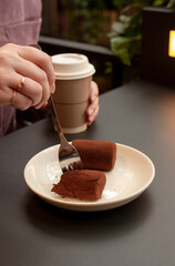 woman eating cakes and drinking coffee in cafe at black table