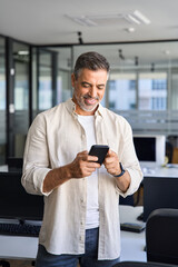 Vertical portrait of middle aged Latin or Indian business man using phone mobile technology...
