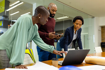 African american architects discussing project ideas over laptop on desk in meeting room