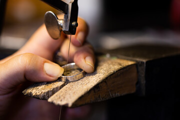 Close up of hands of caucasian female worker making jewellery using tools at jewellery workshop