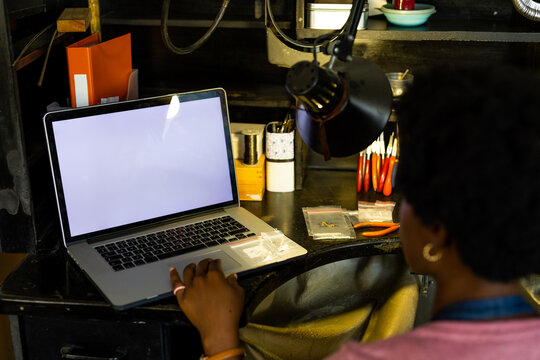 African american female worker using laptop with copy space at jewellery workshop