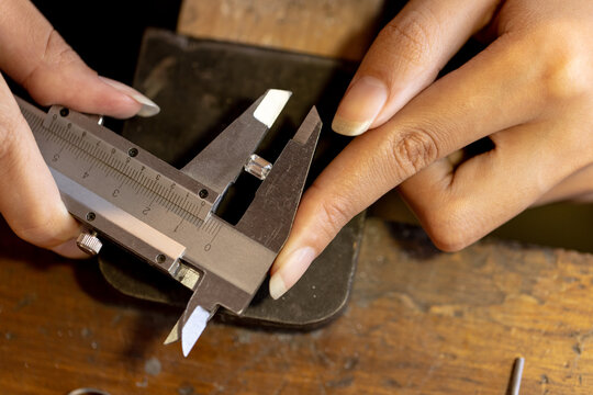 Close up of hands of biracial female worker making jewellery using tools at jewellery workshop - Powered by Adobe