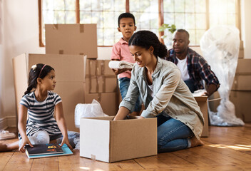 Family, moving and packing boxes into home living room together with children, mom and dad. Property, real estate investment and house move with couple, kids helping box and cardboard unpacking