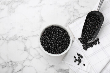 Fototapeta na wymiar Bowl and scoop of raw black beans on white marble table, flat lay. Space for text