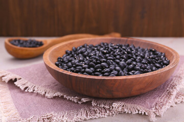 Fototapeta na wymiar Bowl of raw black beans on table, closeup