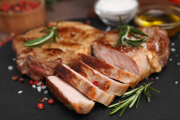 Pieces of delicious fried meat with rosemary and spices on slate plate, closeup