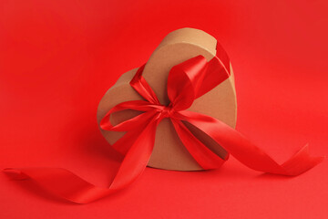 Beautiful heart shaped gift box with bow on red background